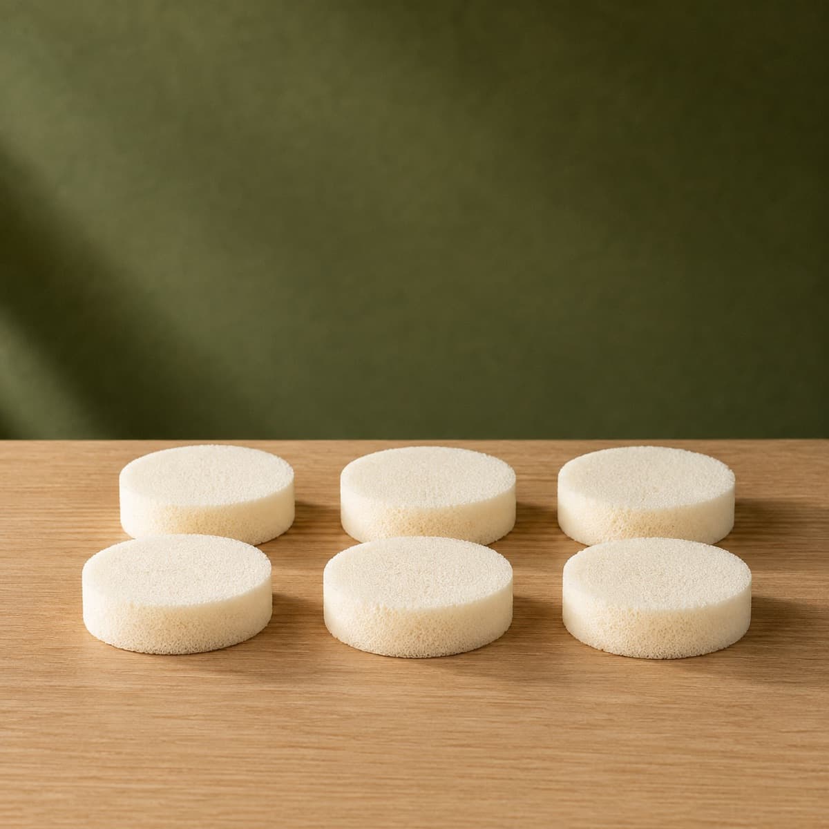 Applicator Sponge Set of 6 — wax-white packaging on an oak surface against a moss-green background